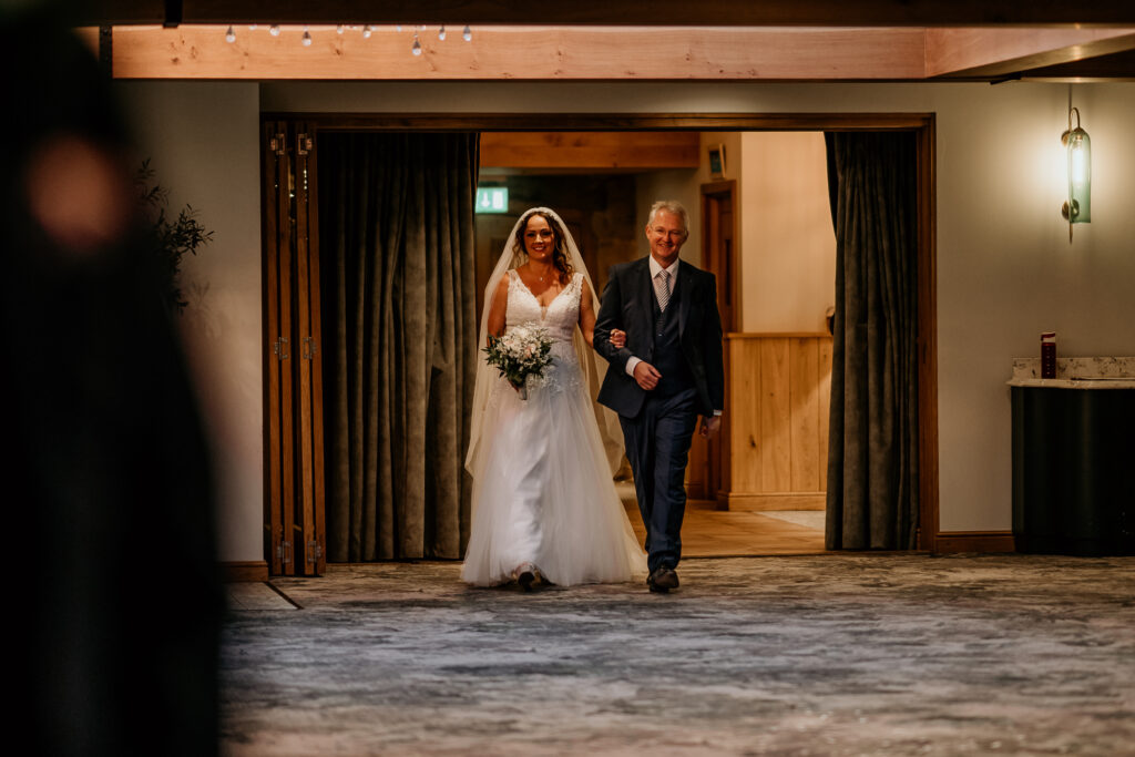 father of bride and bride walking down aisle at peak edge hotel