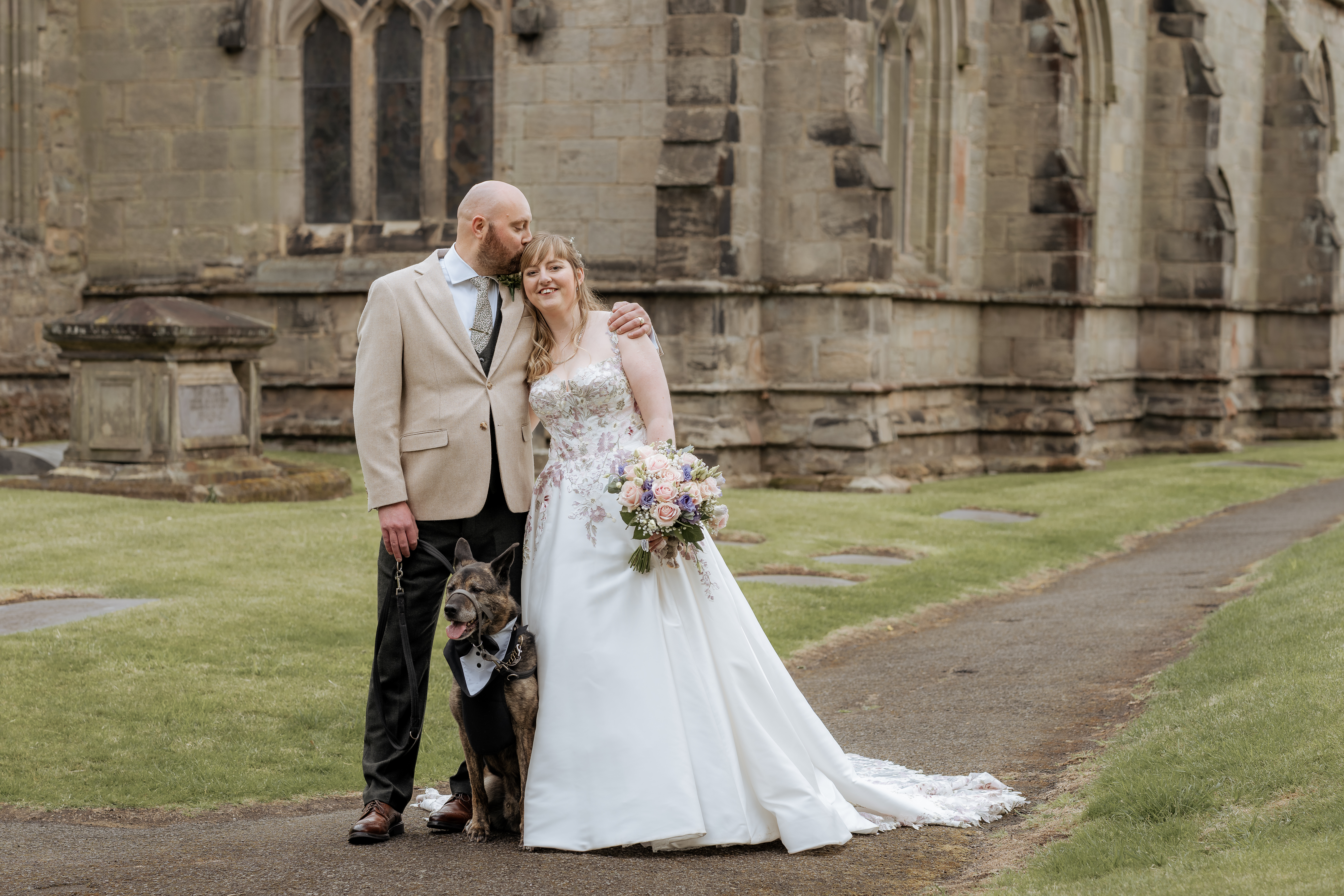 Bride and groom with dog outside church on wedding day